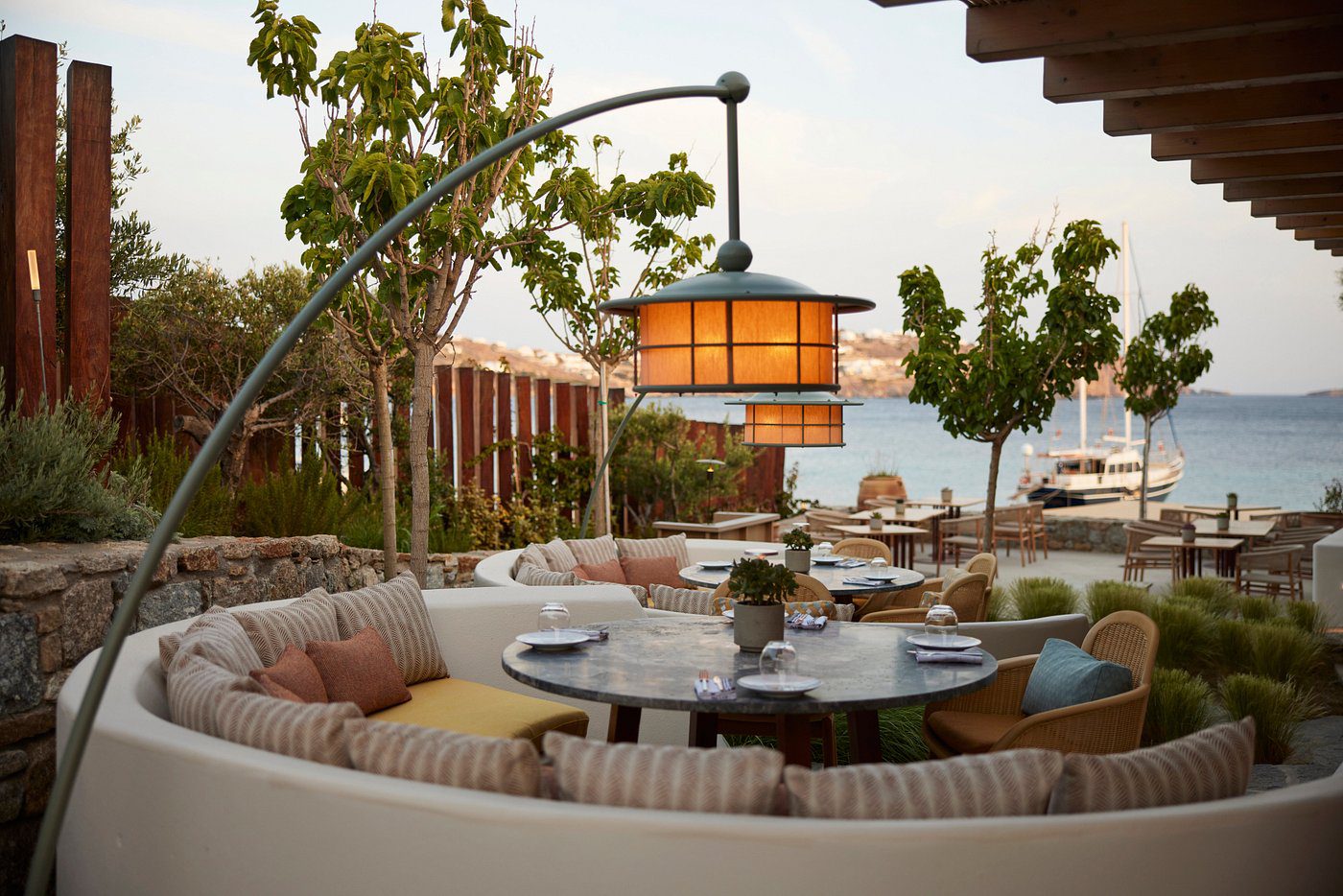 Cozy outdoor dining area with cushioned seating and warm lantern lighting.