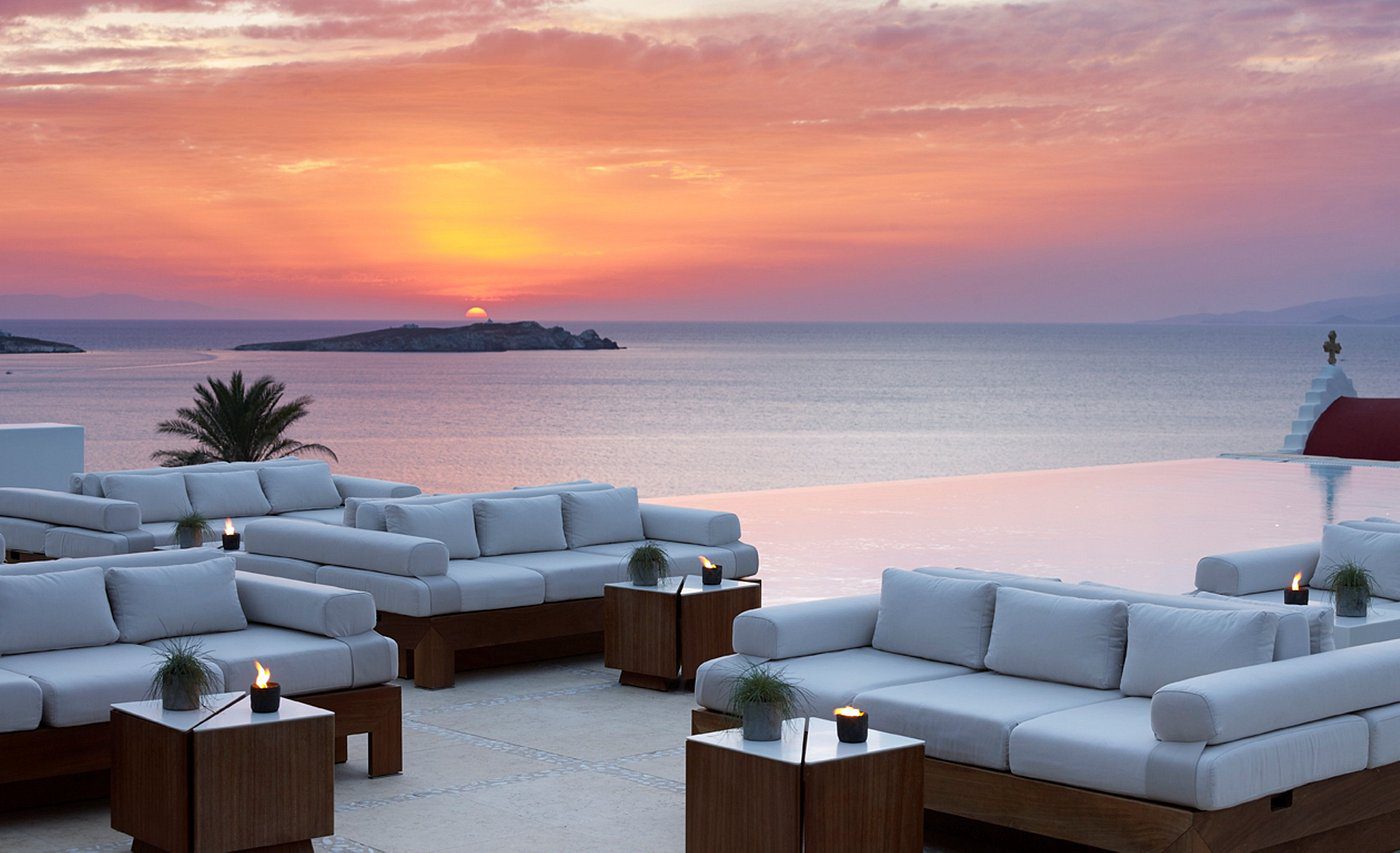 Soft evening light over Bill and Coo Mykonos with calm sea views and golden sky.