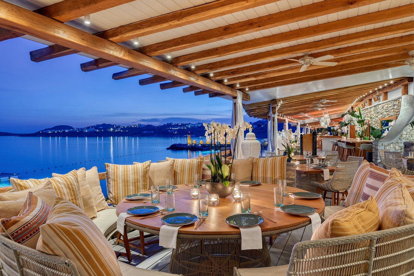 Elegant waterfront restaurant seating with cozy cushions and ambient lighting.
