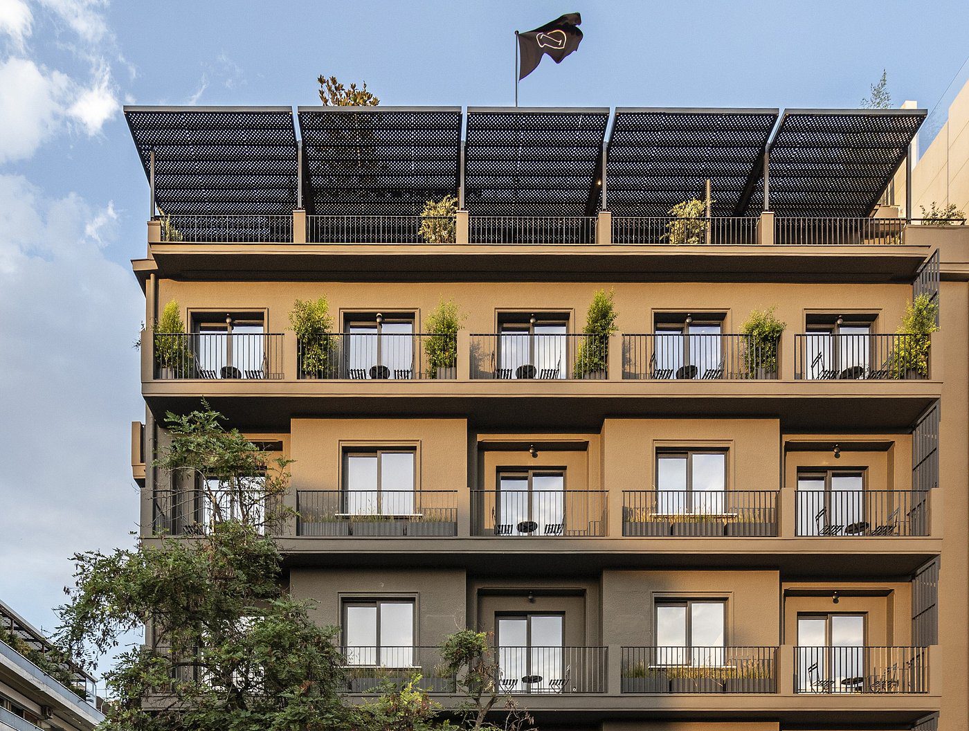 Modern apartment building with balconies and solar panels on the roof.