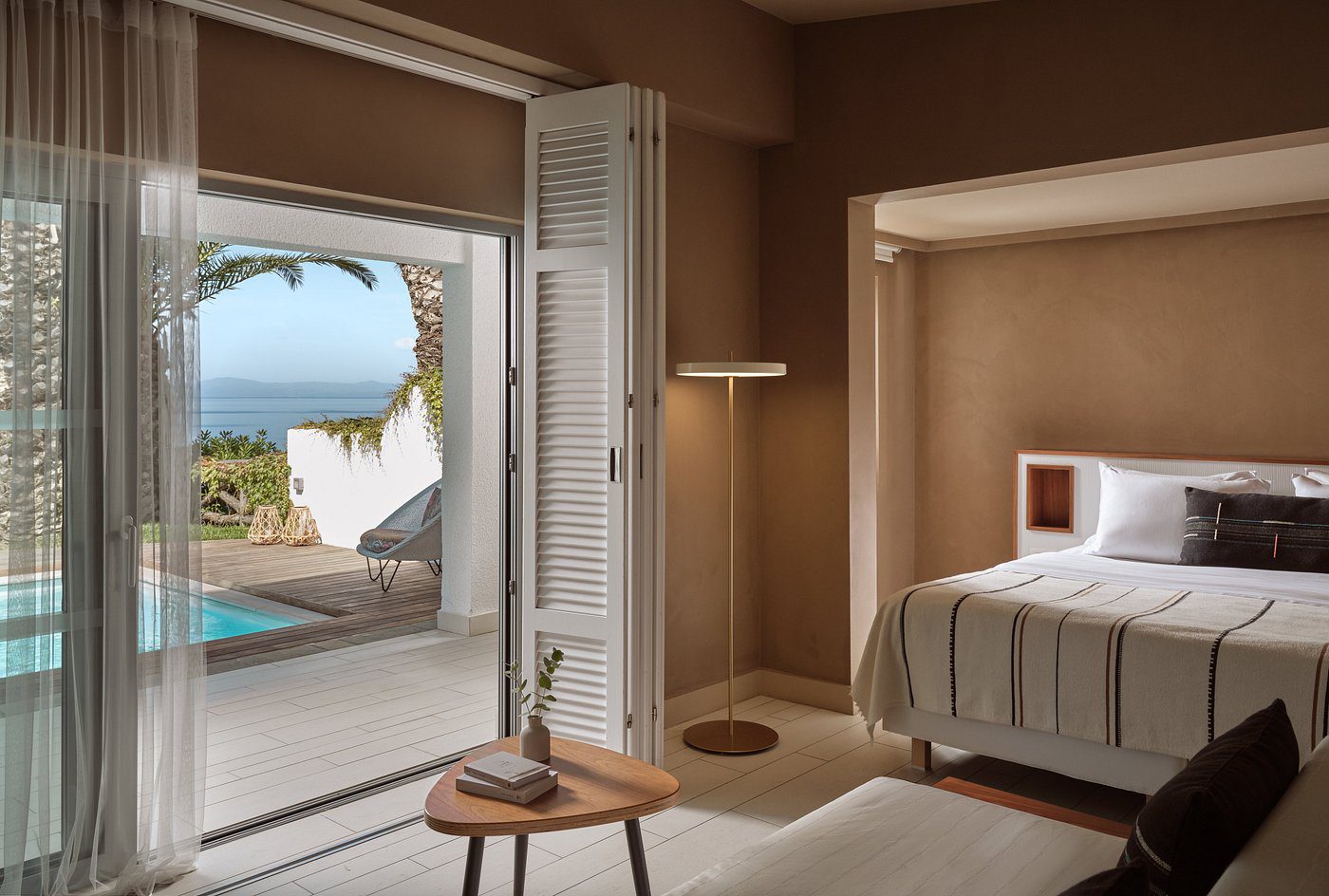 Cozy bedroom with open doors to a pool and ocean view.