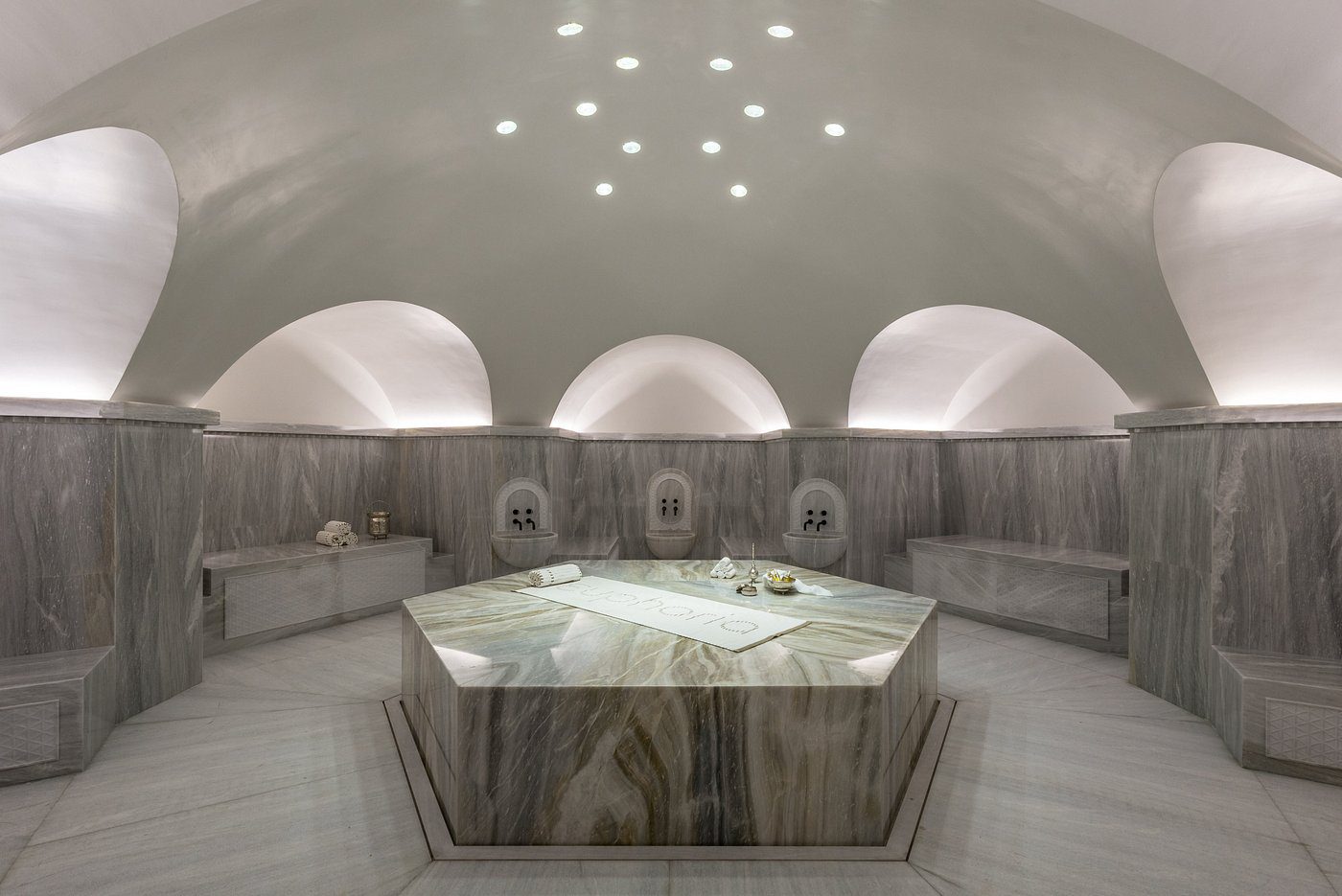 Luxurious marble steam room with ambient lighting and hexagonal centerpiece.