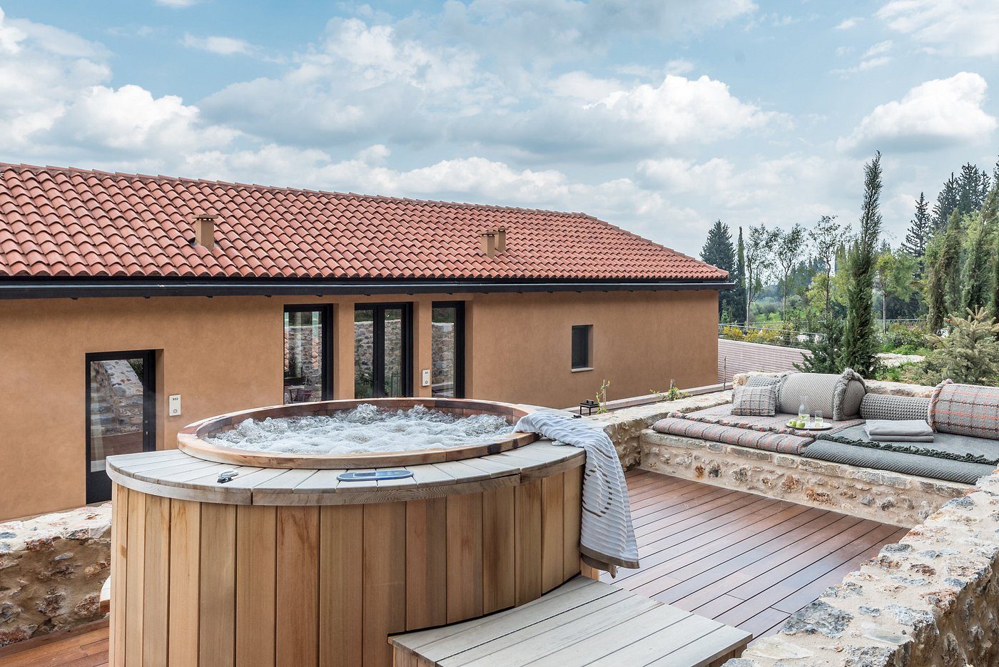 Outdoor wooden hot tubs on a rooftop terrace with a house in the background.