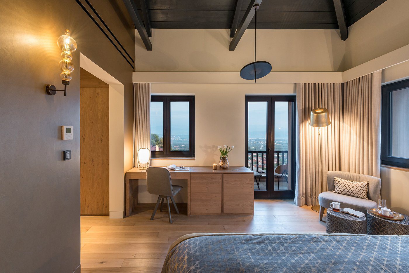 Cozy bedroom with wooden accents and a balcony view at sunset.
