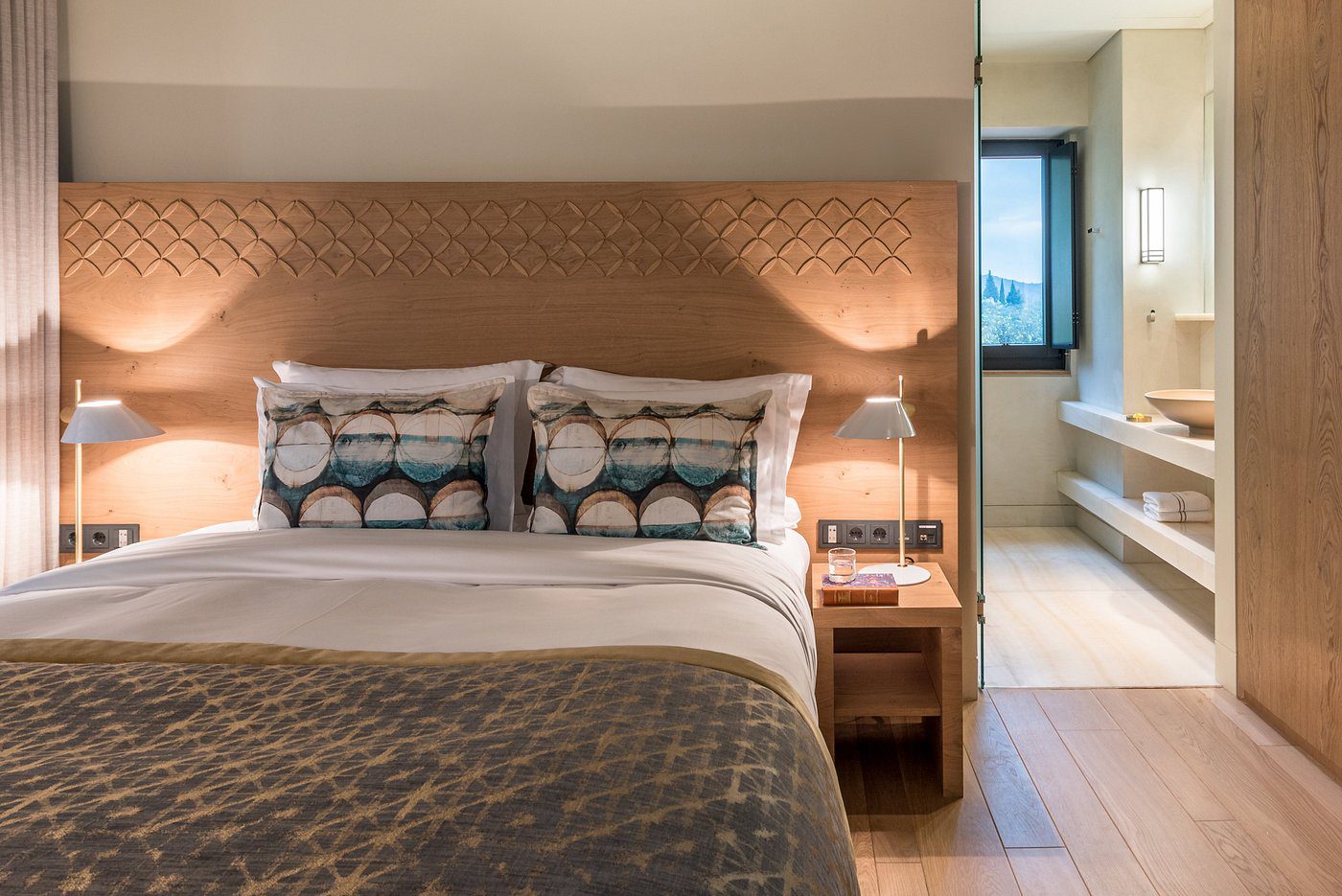 Cozy bedroom with a stylish bed, patterned pillows, and warm lighting.