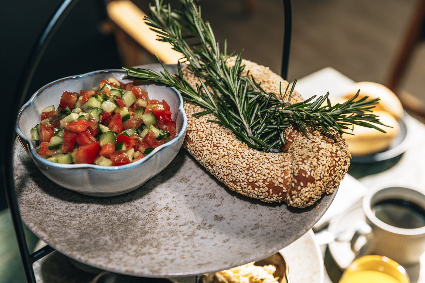 A sesame-covered breadstick garnished with rosemary and a bowl of fresh salsa.