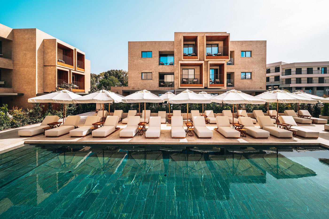 Modern resort with poolside lounge chairs and umbrellas.