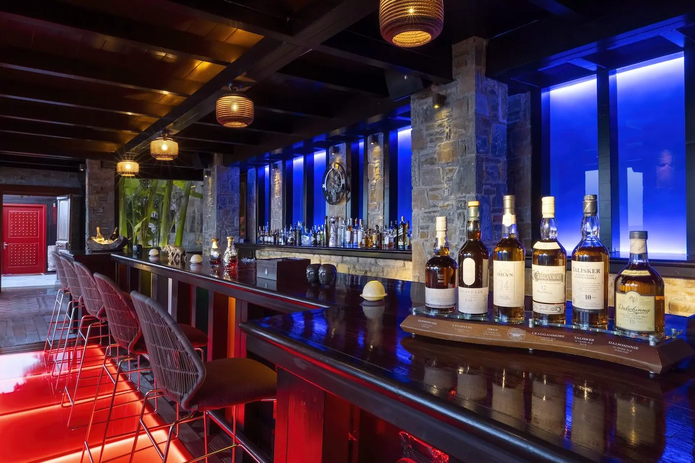 A stylish bar with vibrant lighting and bottles on display.