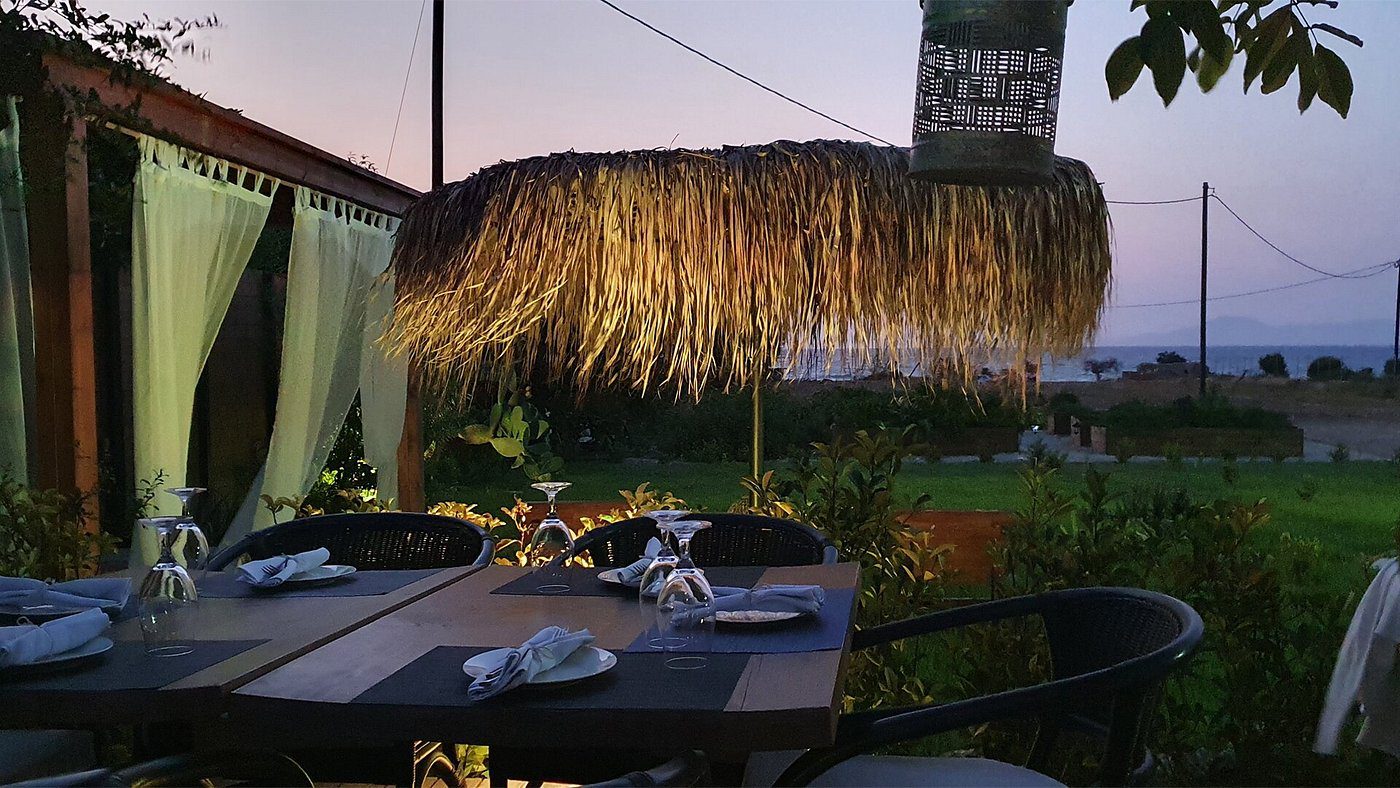 Cozy outdoor dining area under a thatched roof at dusk.