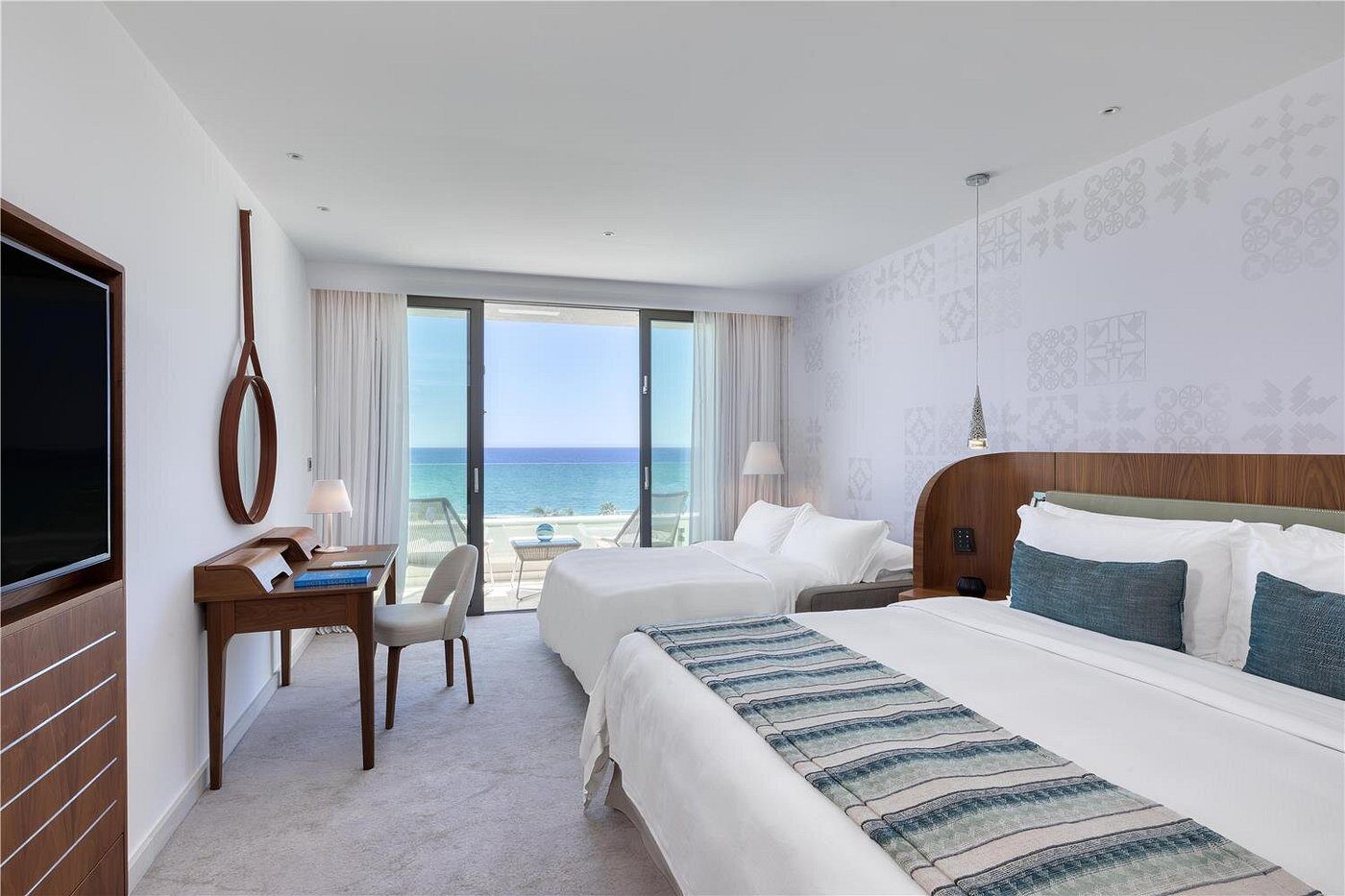 Bright hotel room with ocean view and two beds.