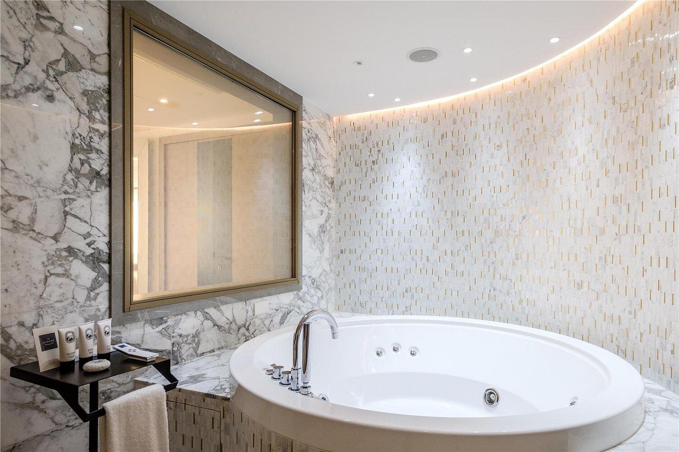 Luxurious bathroom with a large oval bathtub and marble walls.