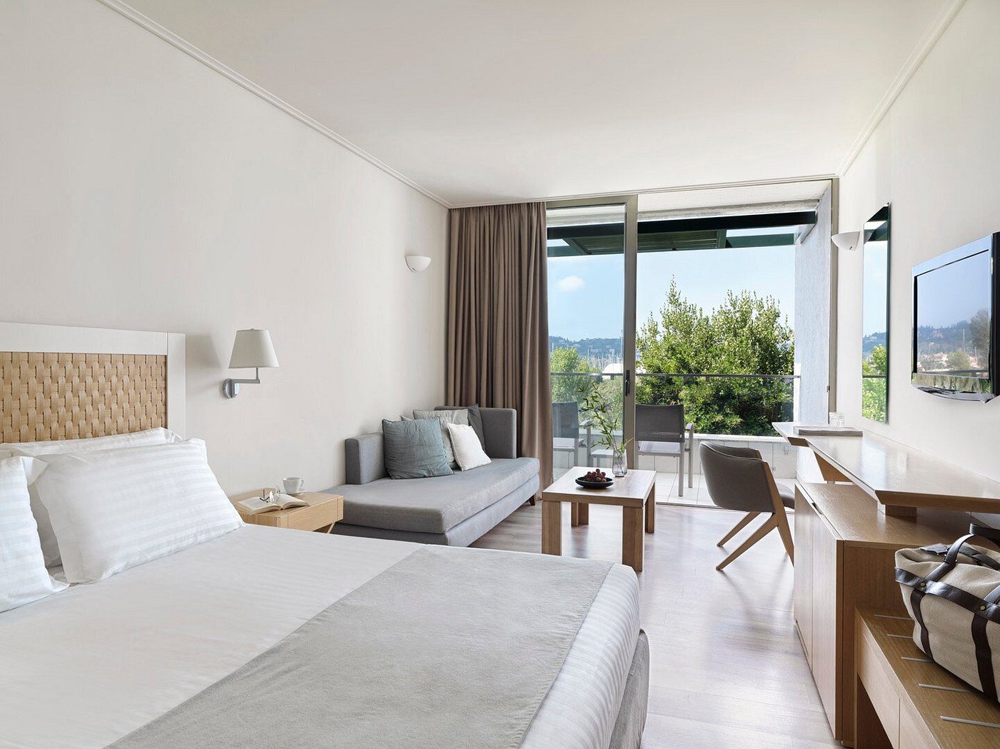 Modern hotel room with a large bed and balcony view.