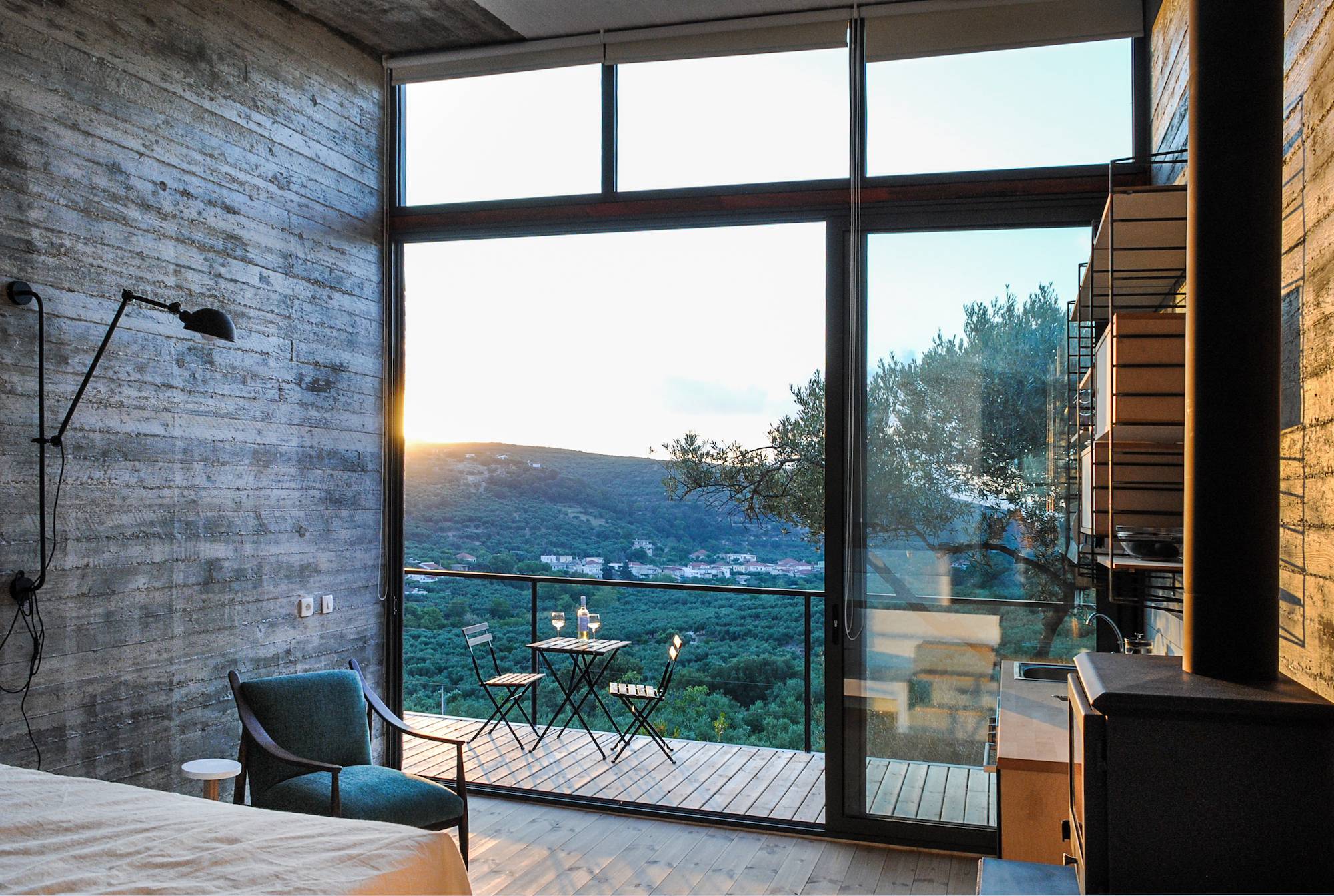 Modern room with large glass doors opening to a balcony and scenic mountain view.