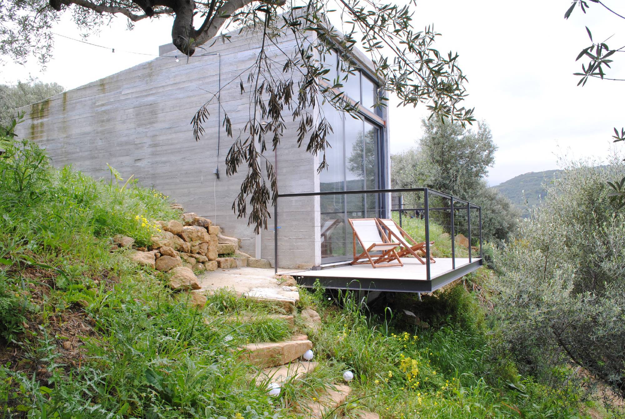 Modern house with a cantilevered deck in a lush green setting.