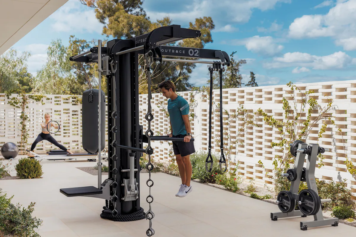 Man doing pull-ups with chains on outdoor gym equipment.