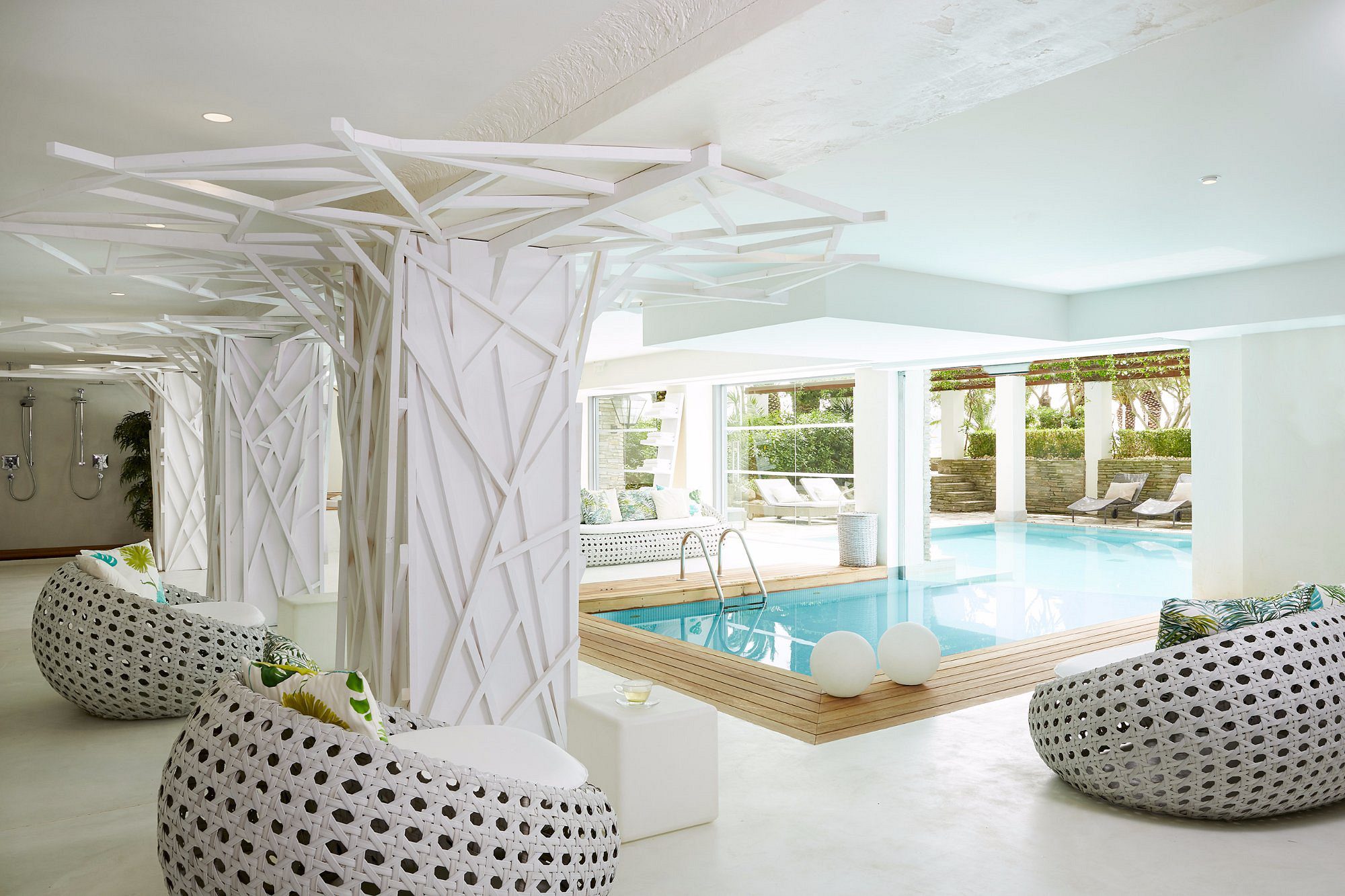 Modern indoor pool area with stylish white seating and natural light.