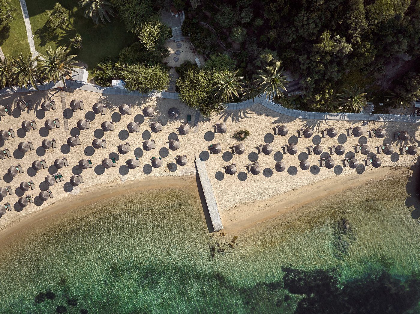 Aerial view of a beach with sun umbrellas and clear turquoise water.