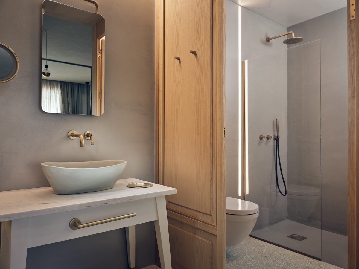 Minimalist bathroom with a white sink, wooden cabinets, and a walk-in shower.