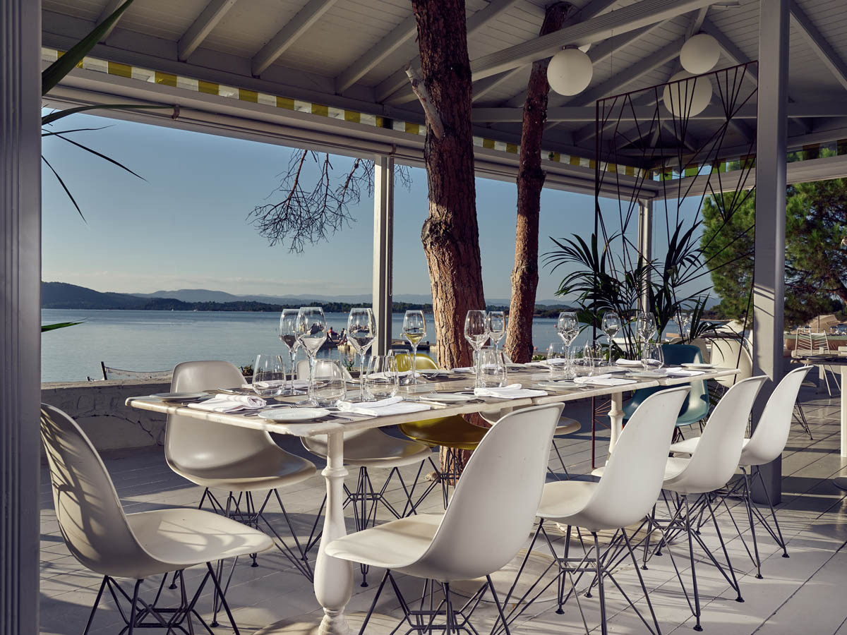Elegant outdoor dining setup with white chairs and a scenic lake view.