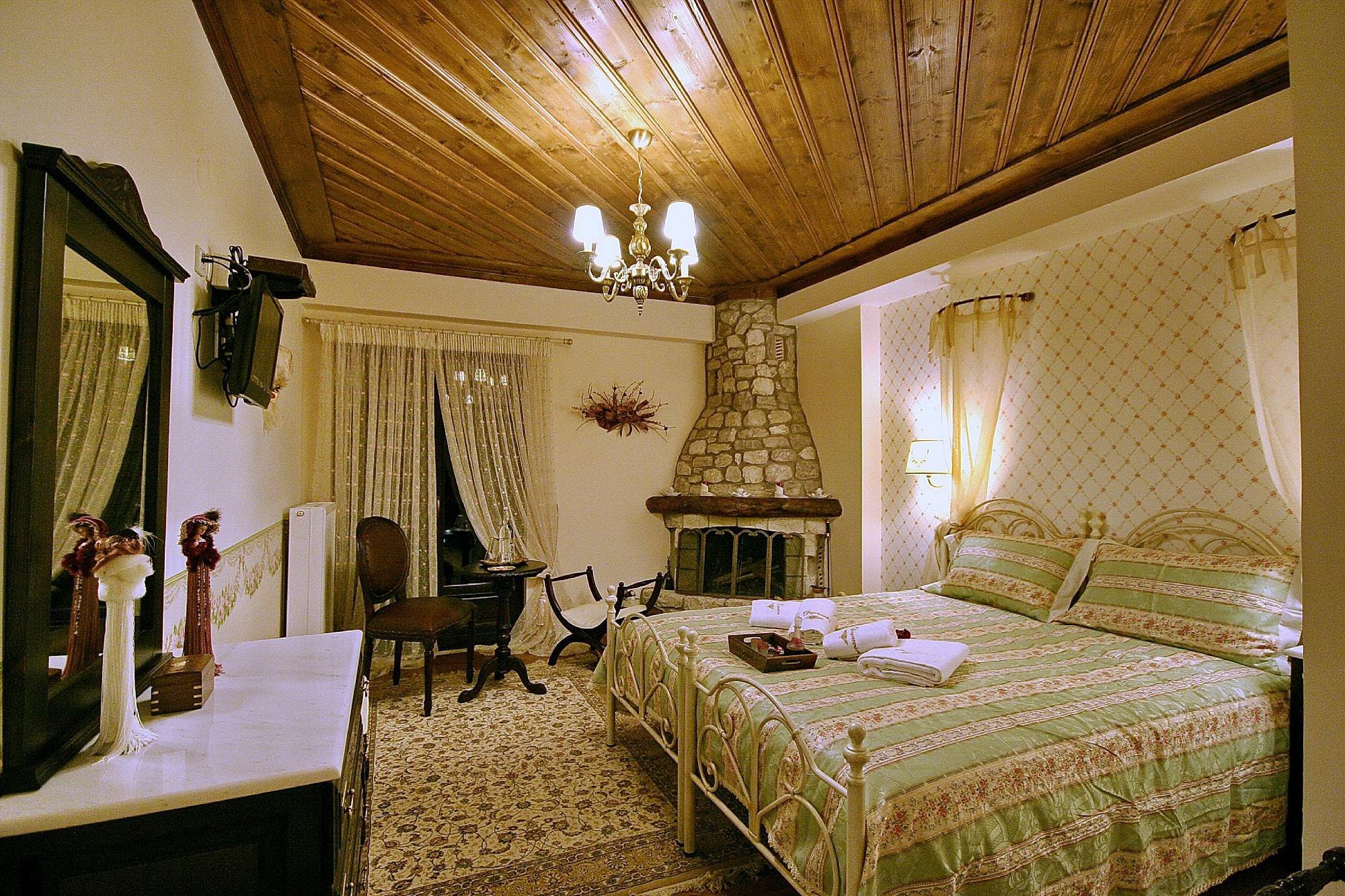Cozy bedroom with wooden ceiling and stone fireplace.
