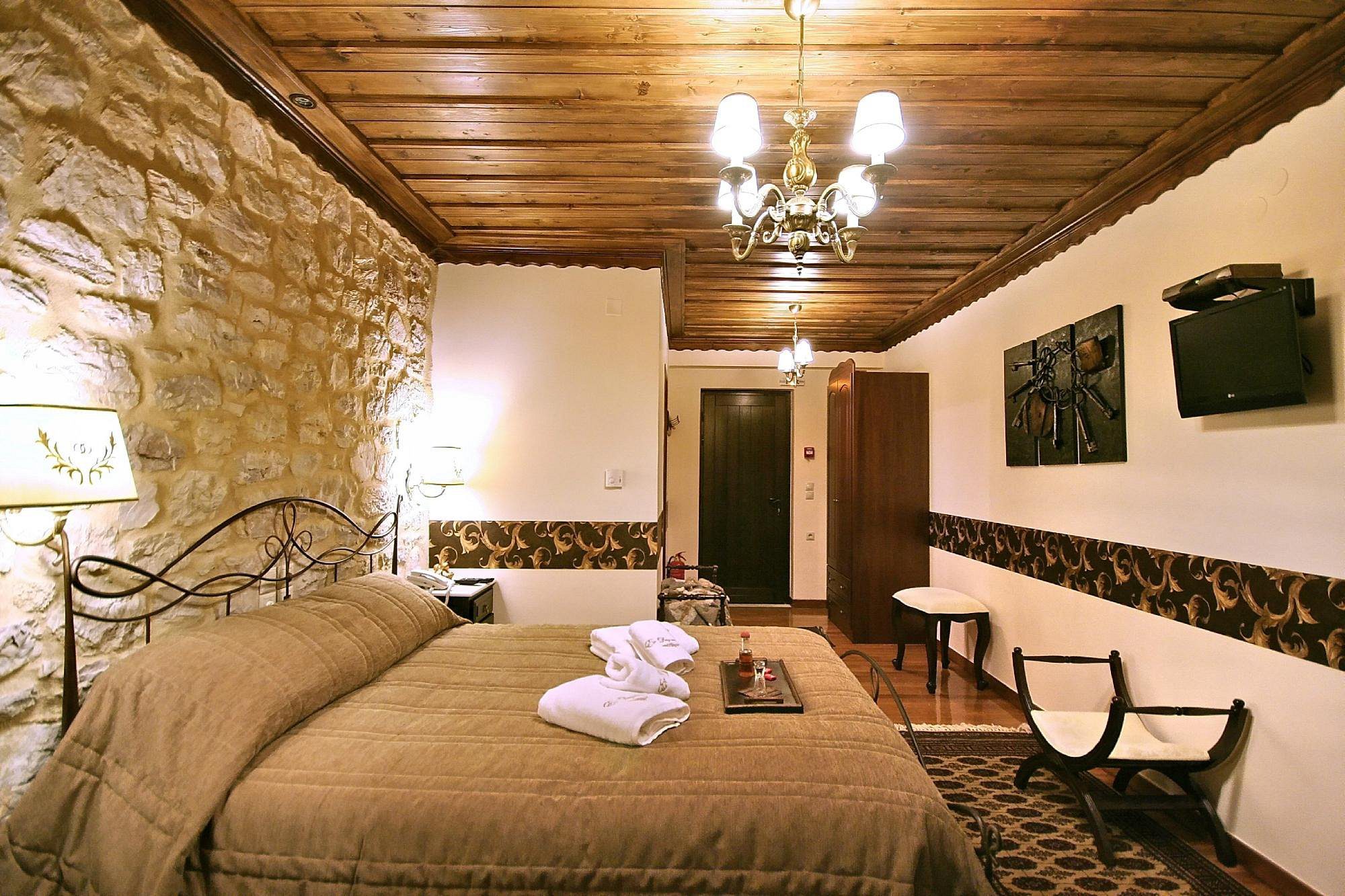 Cozy bedroom with rustic stone walls and wooden ceiling.