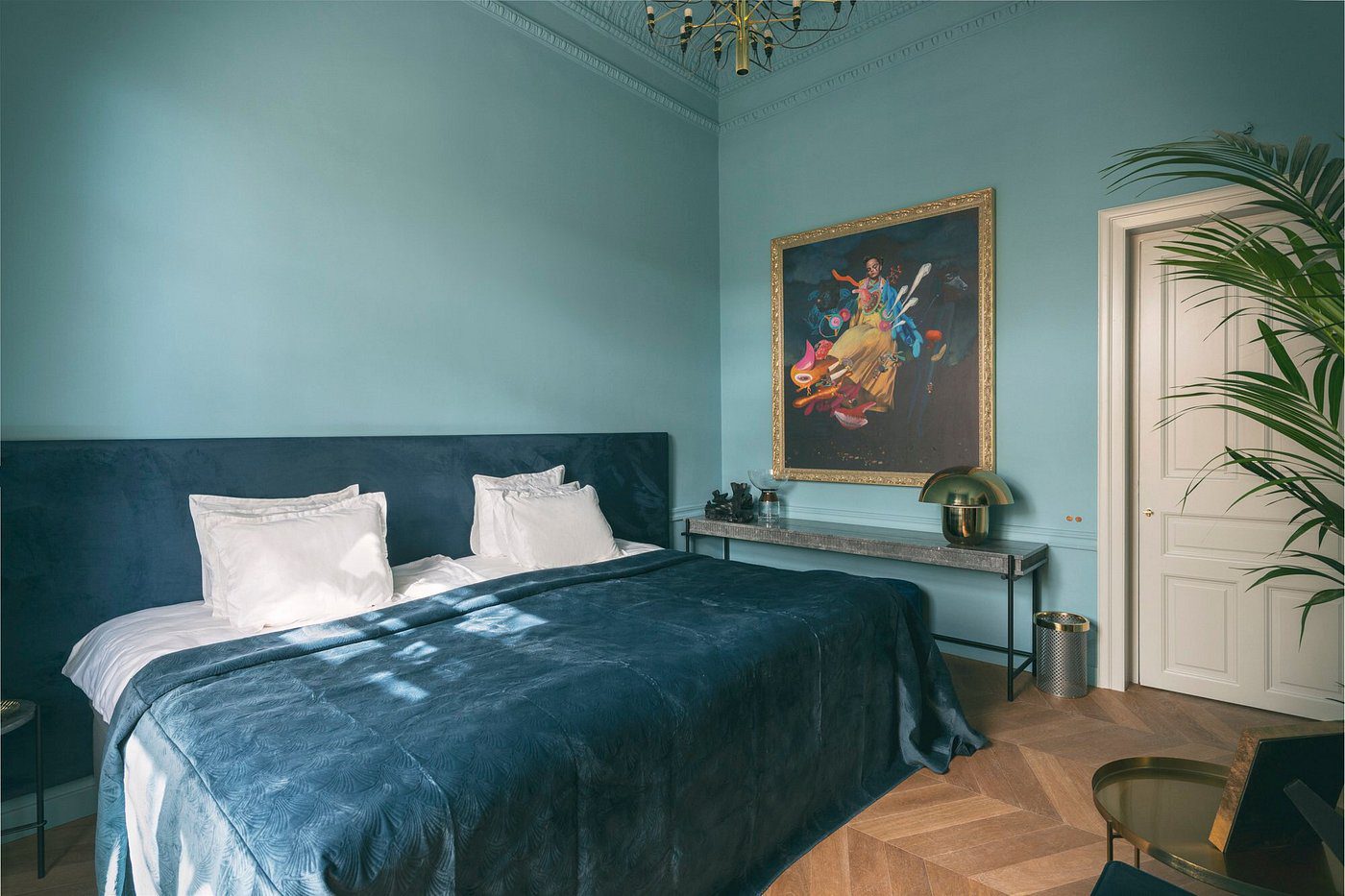 Elegant bedroom with teal walls, velvet bedding, and classical art.