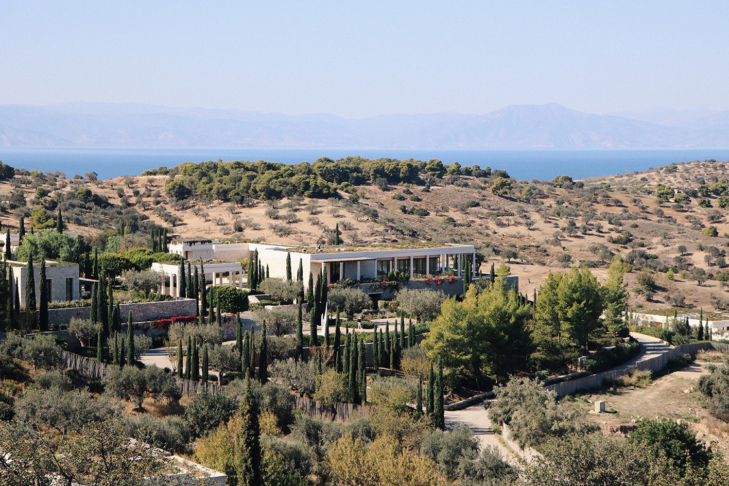 Modern buildings in a dry, hilly landscape with sparse vegetation.