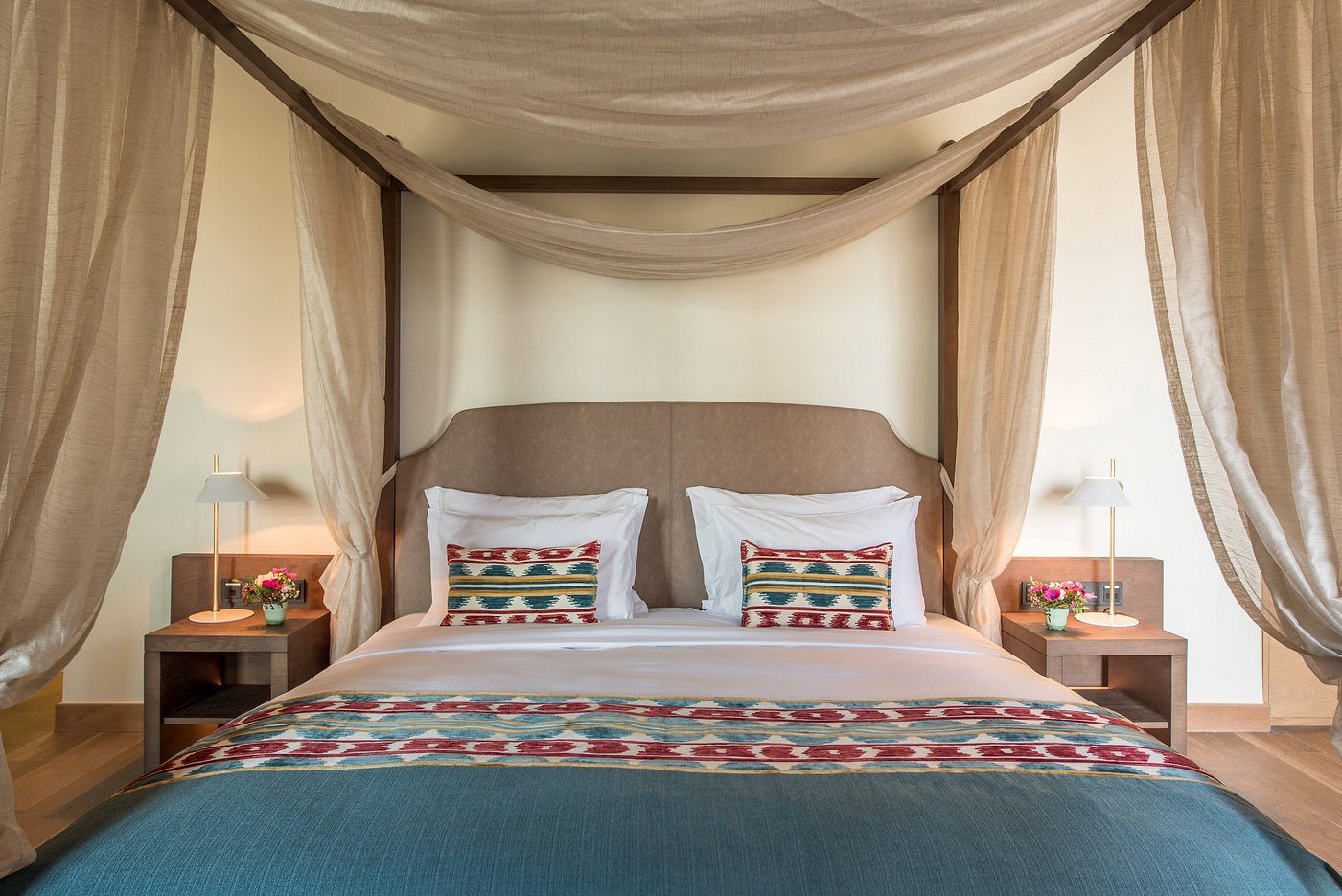 Elegant canopy bed with patterned pillows and soft lighting.