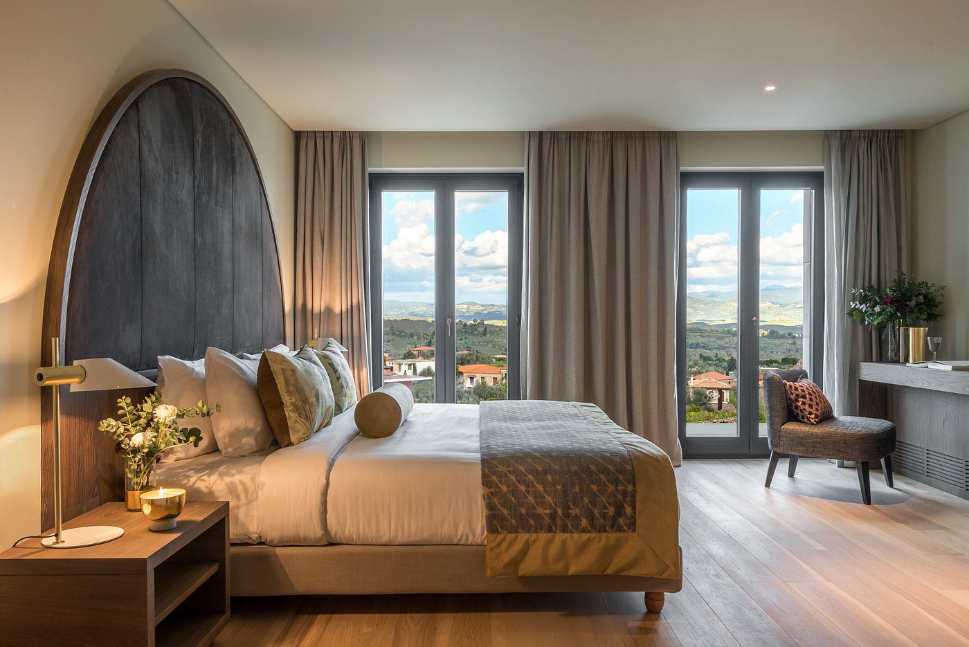Luxurious hotel room with a large bed and city view windows.