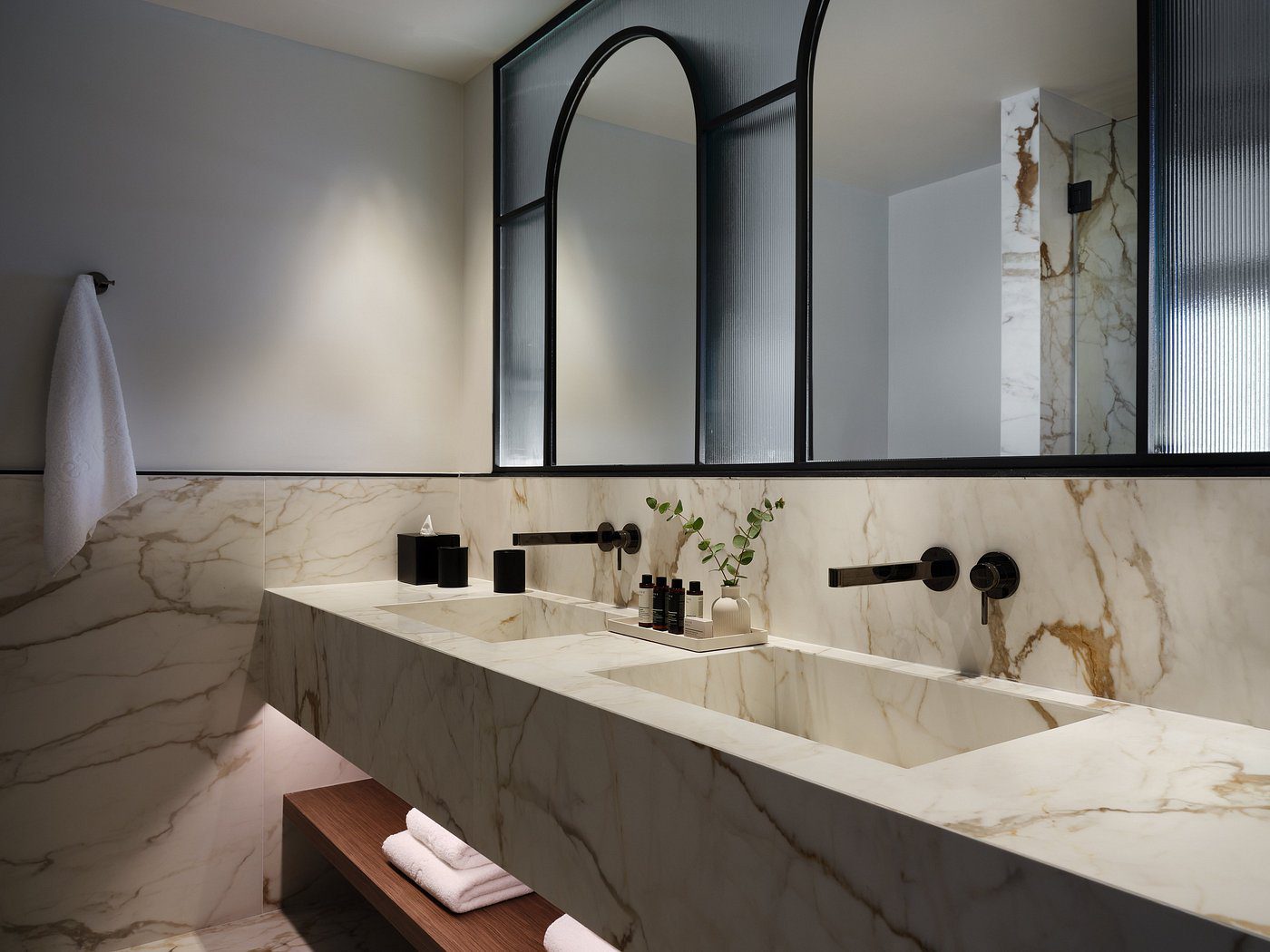 Modern bathroom with a marble double sink and two arched mirrors.