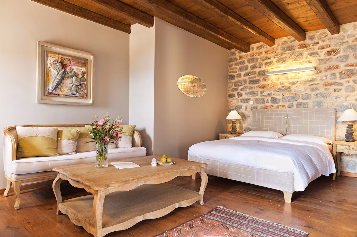 Cozy rustic bedroom with wooden beams and stone wall.