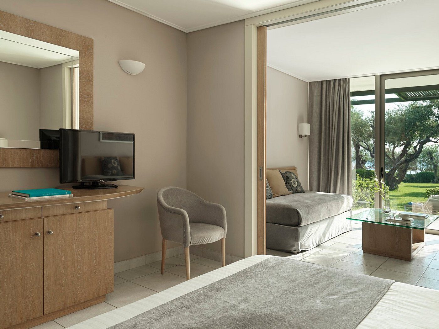 Modern living room with neutral tones, a TV, and a sliding glass door.