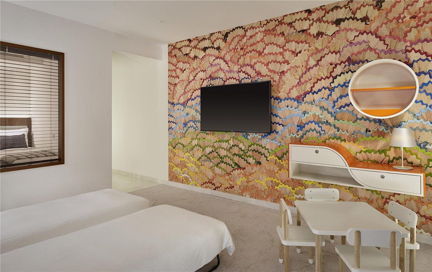 Modern hotel room with a wall-mounted TV and artistic wallpaper.