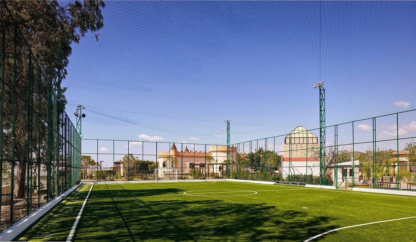 A small soccer field with artificial turf under a clear blue sky.