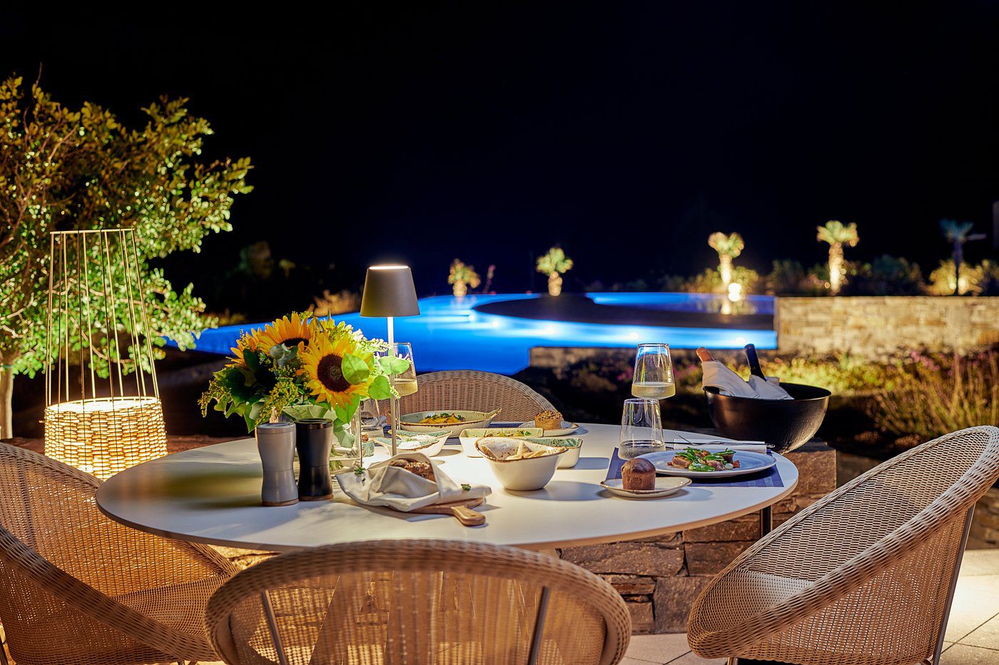 Elegant outdoor dining setup by a pool under night sky.