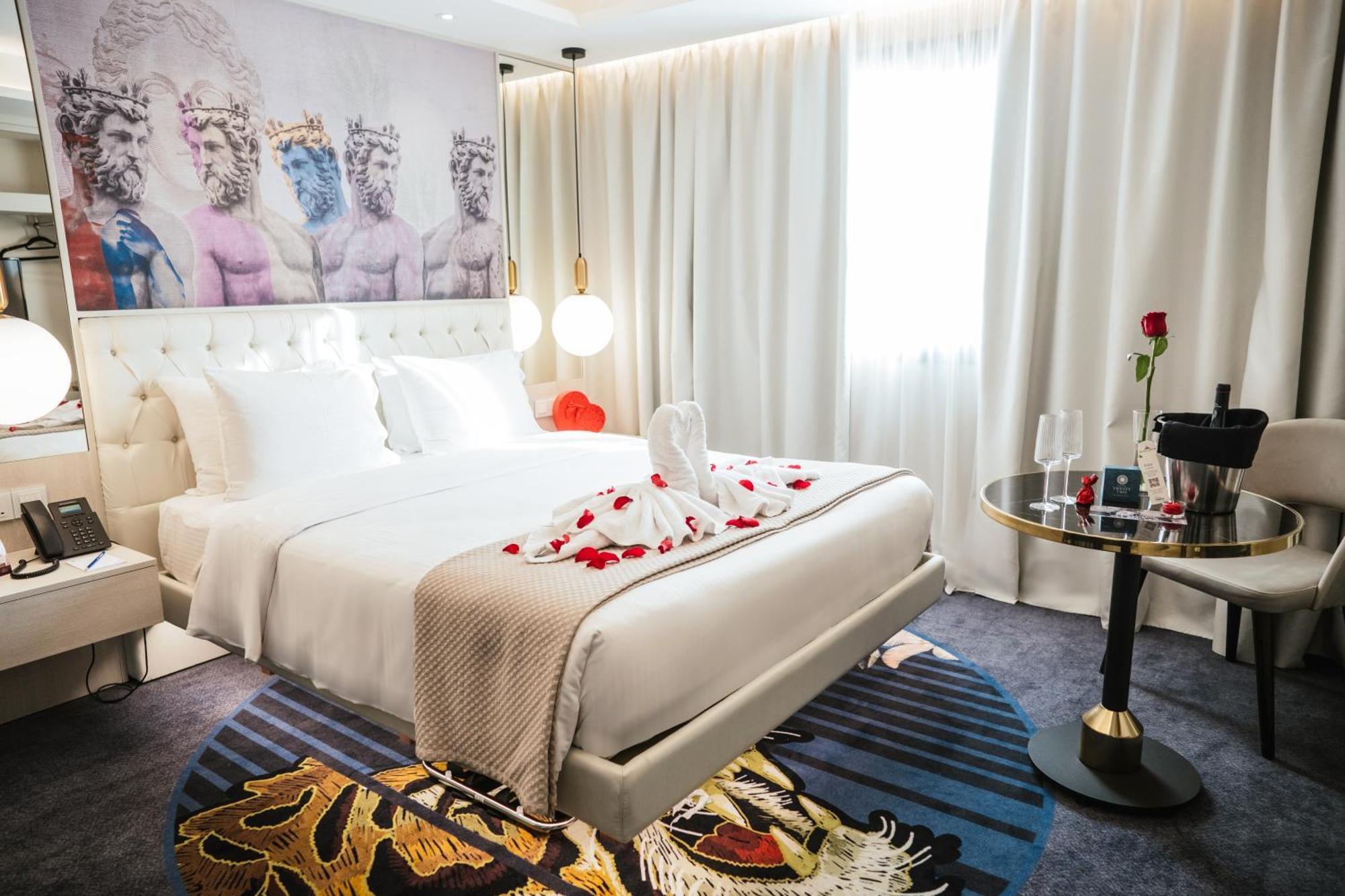 Elegant hotel room with rose petals on the bed and soft lighting.