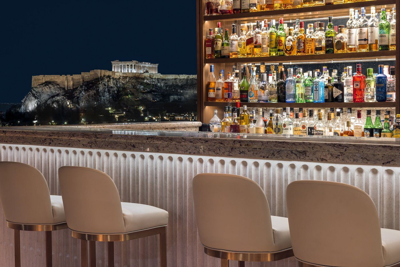 Elegant bar stools in a chic bar with a nighttime city view.
