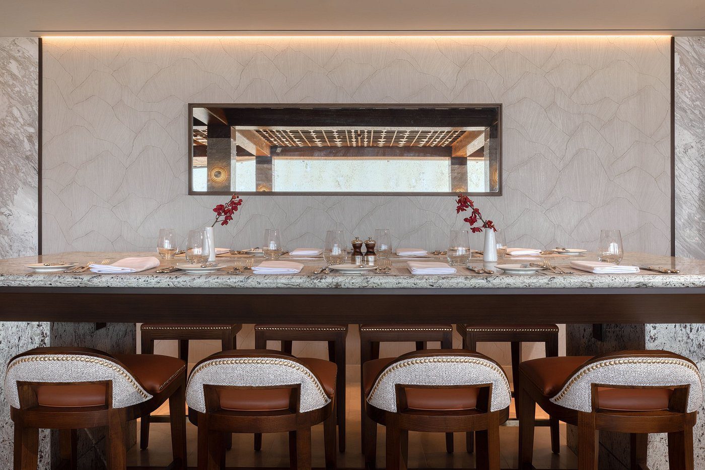 Elegant dining table with cushioned chairs and a large mirror on the wall.