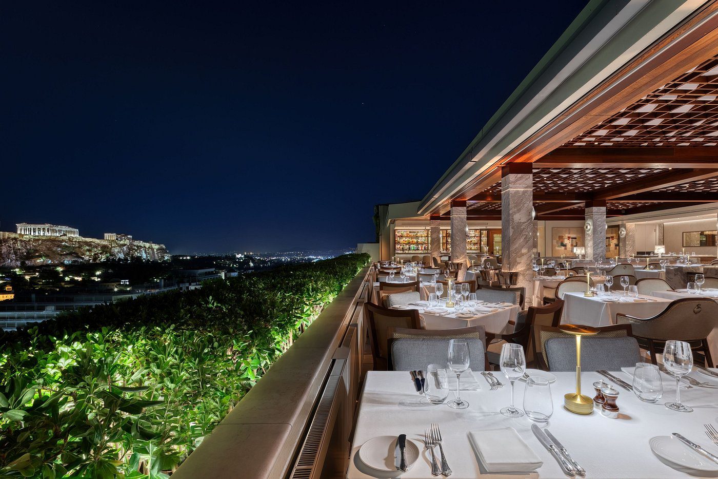 Elegant rooftop restaurant with city night views and neatly set tables.