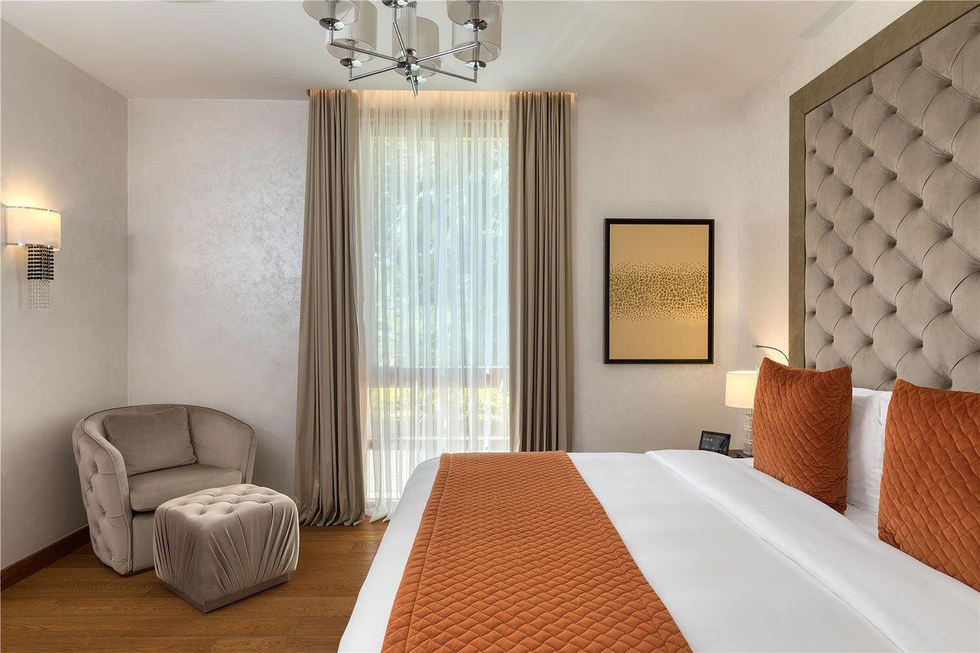 Cozy bedroom with warm tones, featuring an orange bed runner and soft lighting.
