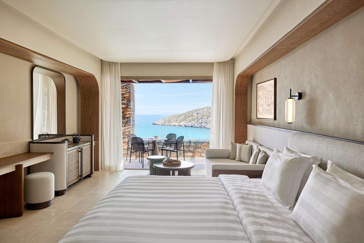 Luxury hotel room with ocean view and balcony seating.