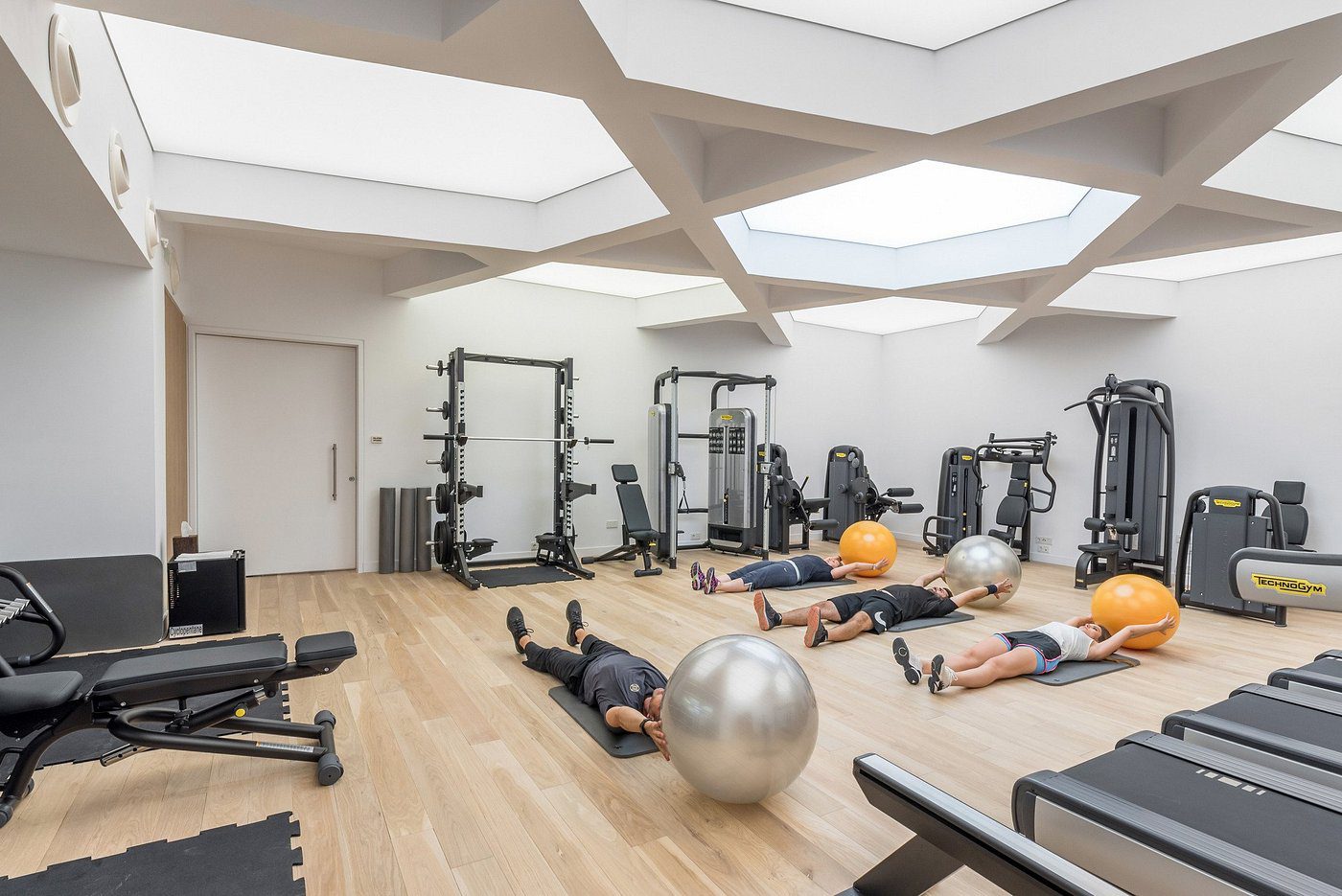 A modern gym with various exercise equipment and people working out.