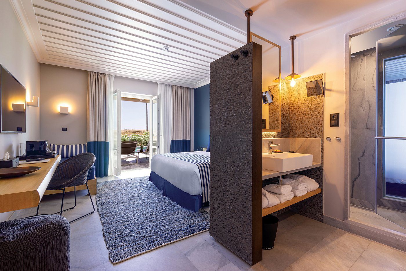 Modern hotel room with a cozy bed and open bathroom.