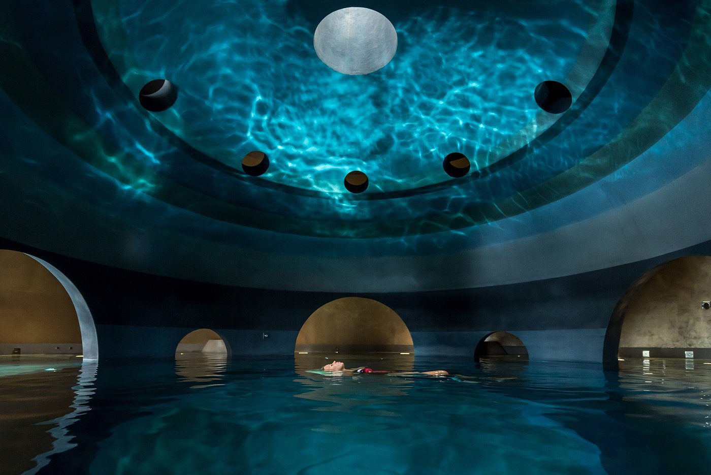 A glowing solar system model with planets suspended in a blue-lit room.