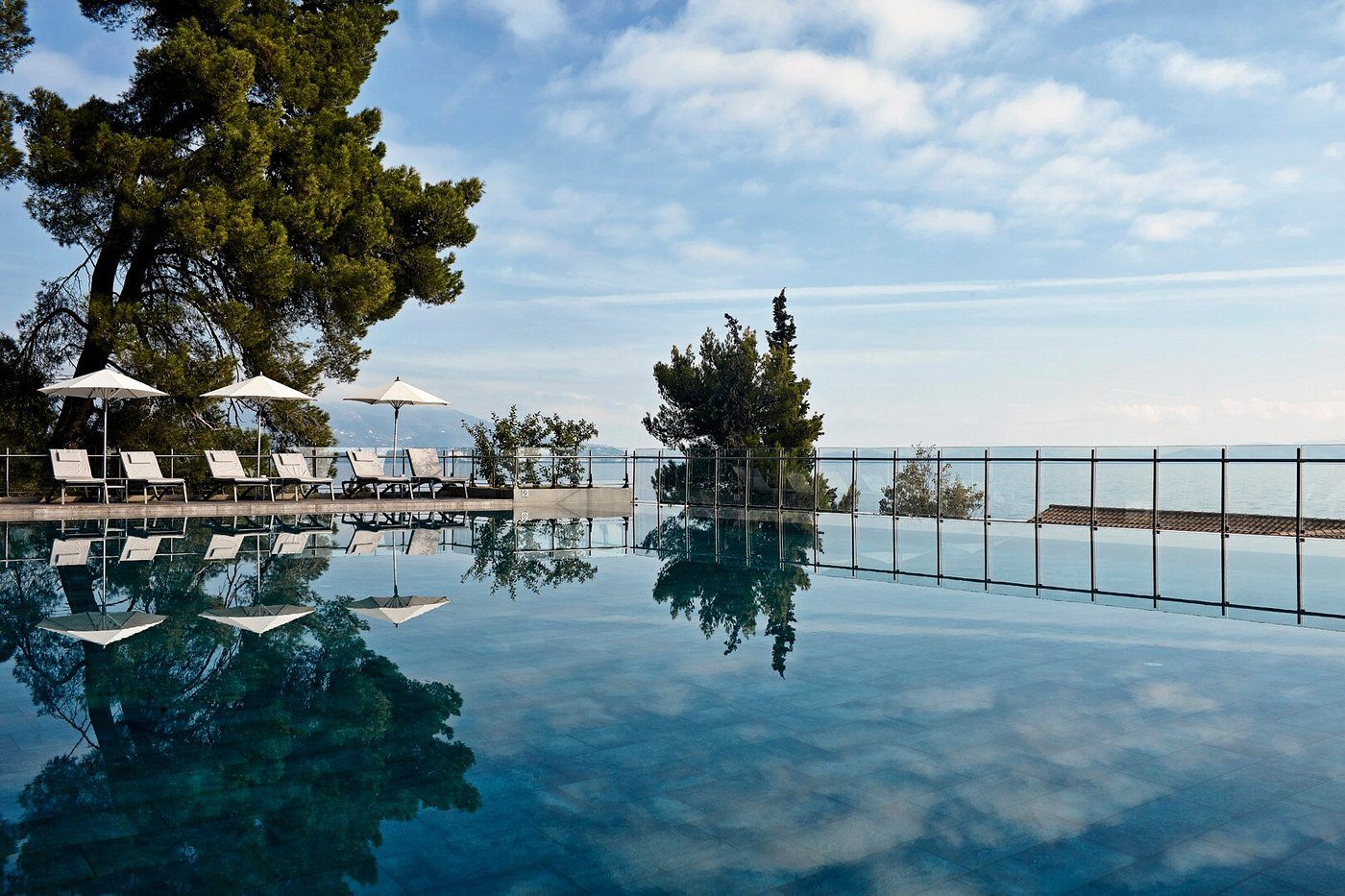 A serene infinity pool overlooking the sea under a blue sky.