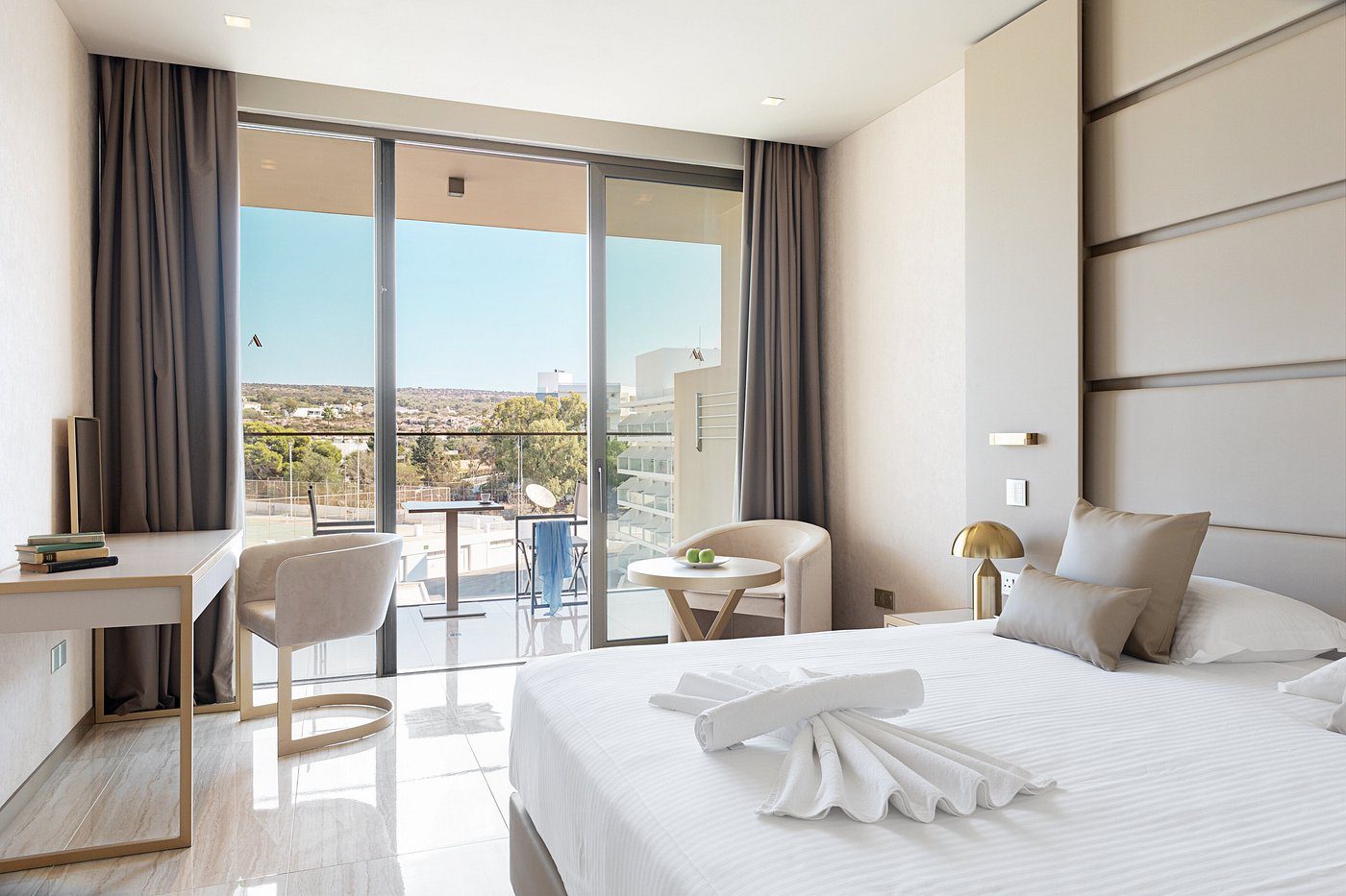 Modern hotel room with balcony and city view.