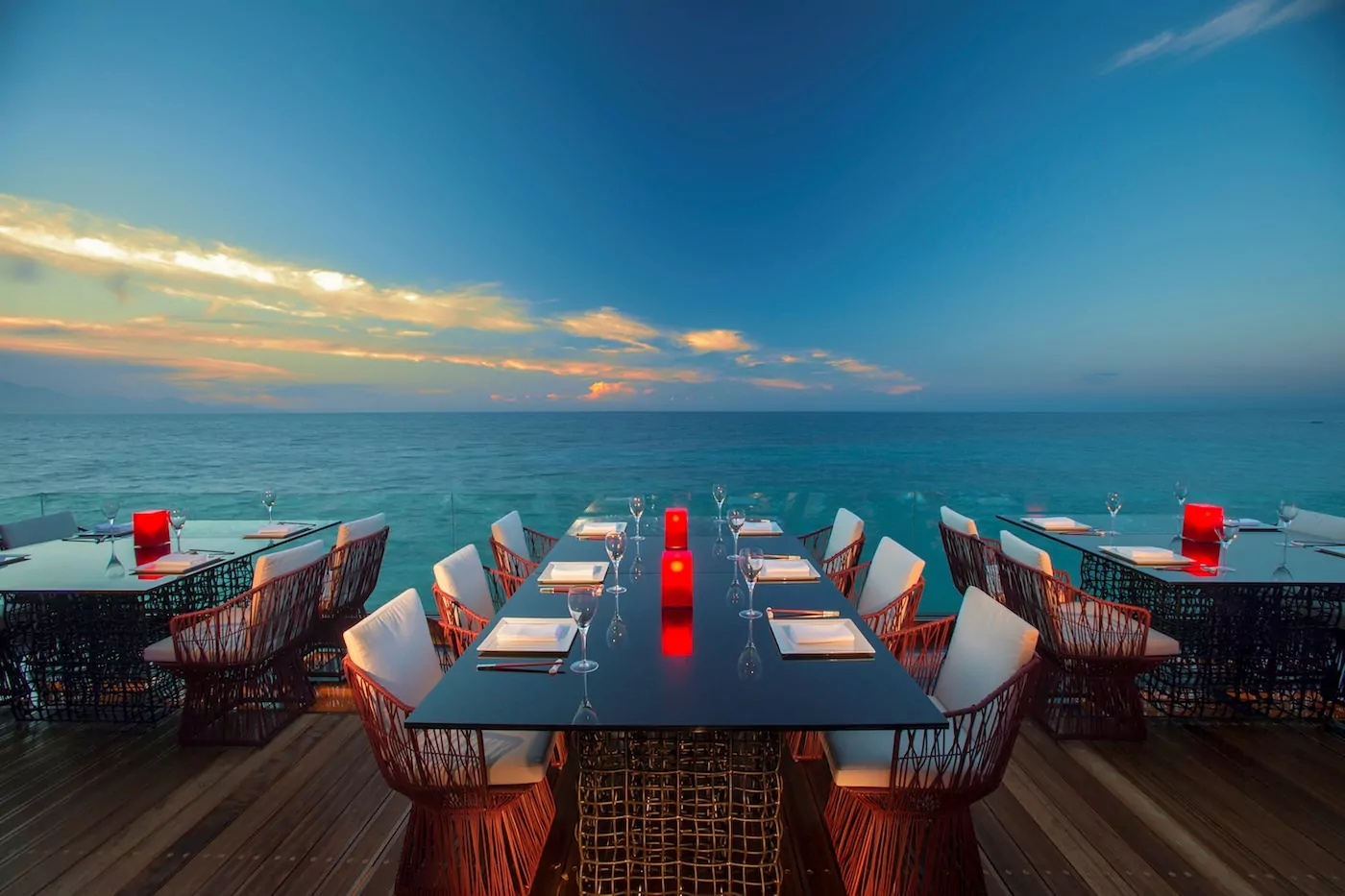 Elegant outdoor dining setup overlooking the ocean at sunset.