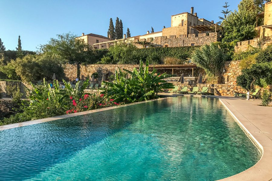 A serene pool with lush greenery and historic buildings in the background.