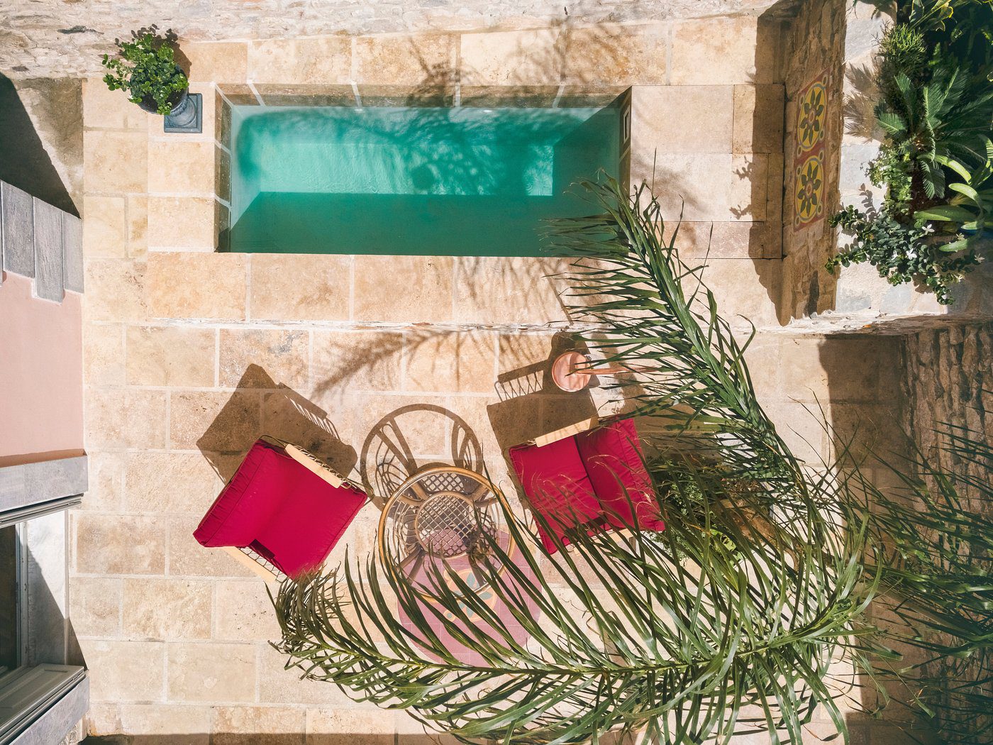 Cozy outdoor seating with a turquoise pool and vibrant red cushions.