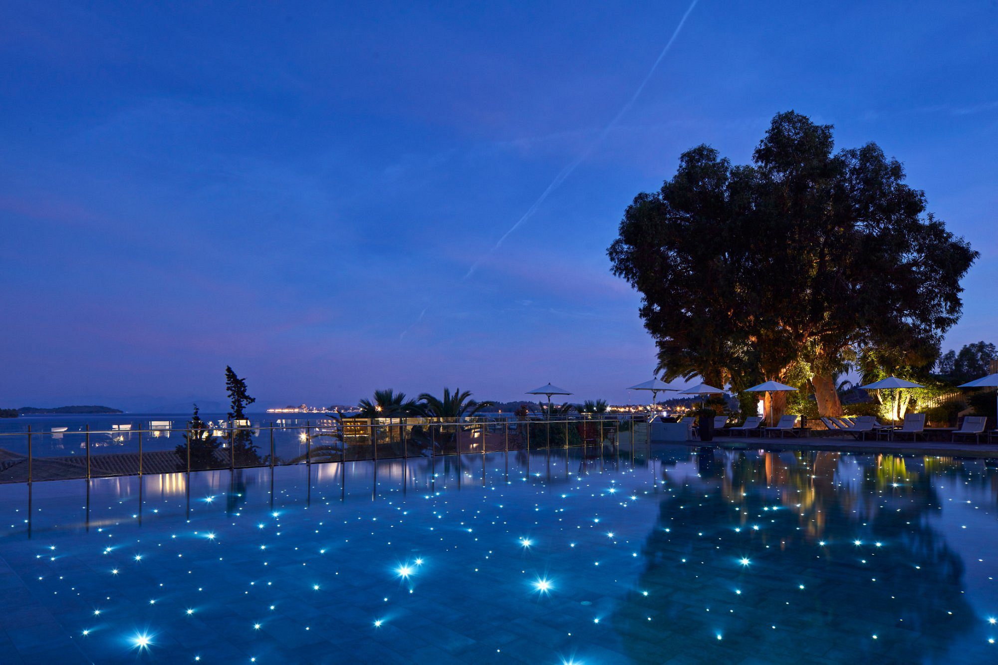 A serene pool glowing with blue lights under a twilight sky.